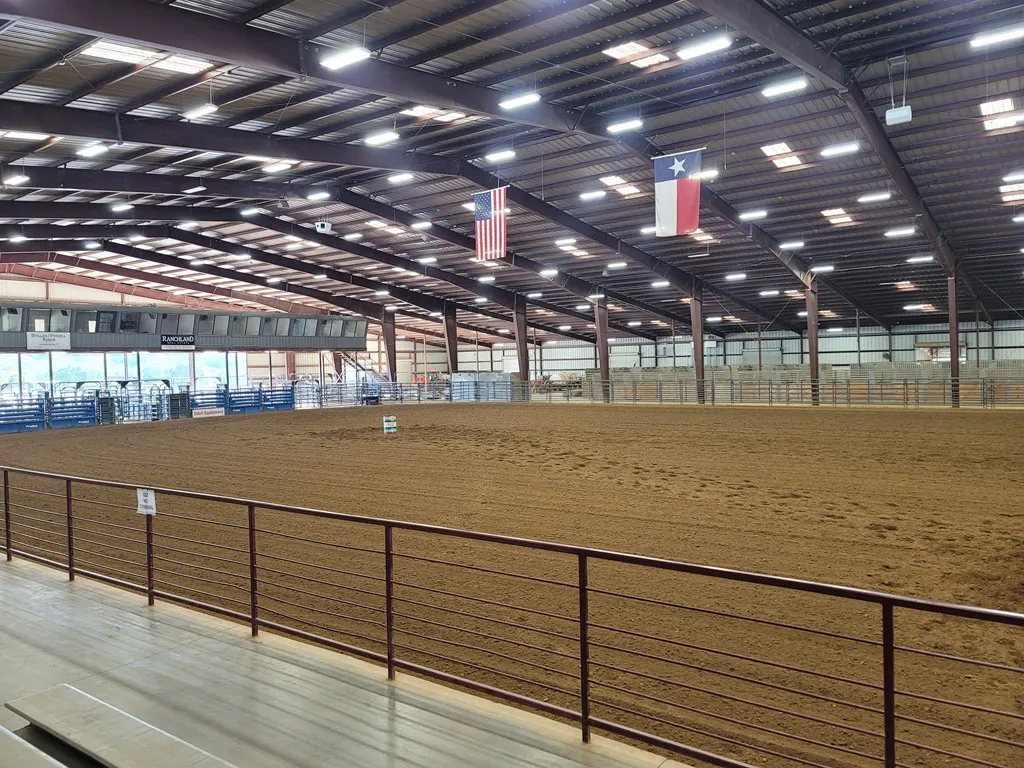 Indoor arena at barrel racing event with American and Texas flags